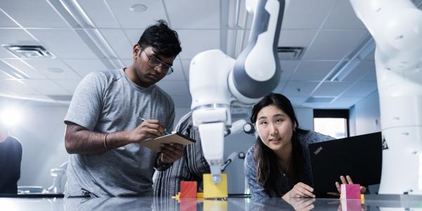 Students looking at a robotic arm.