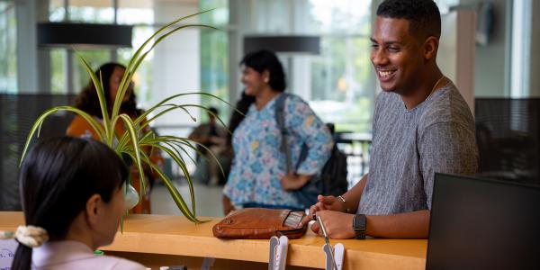 A student asking a question to a staff member at a desk.