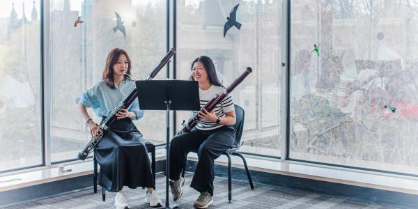 Two students sitting in a classroom getting ready to play their bassoons