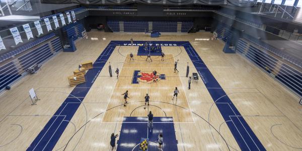 Students playing volleyball in a gym.