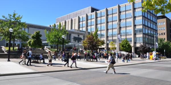 Outside of Sidney Smith building on a summer day with people walking across the road in front of it