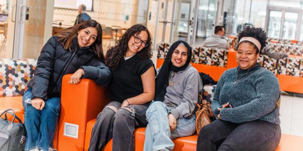 Students smiling for camera sitting on couch.