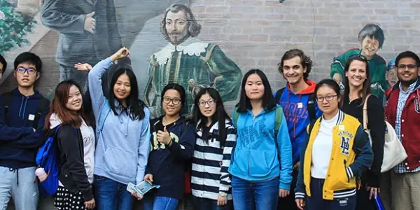 A group of students standing in front of a mural.