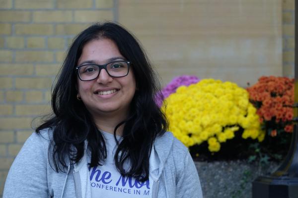 Smiling student standing outside in front of some flowers