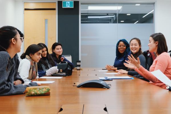 Students having a discussion around a desk.