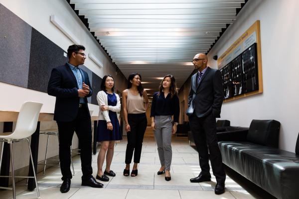 Five students standing in a hallway wearing business attire