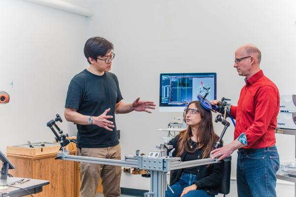 Researchers conduct an experiment in a lab, using specialized equipment while a participant is seated