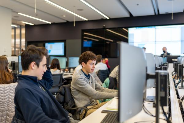 Students sitting in front of a computer in a market simulation lab
