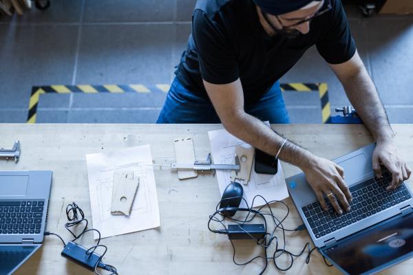 Student working on two laptops with electronic equipment attached to them