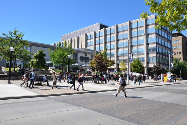 Outside of Sidney Smith building on a summer day with people walking across the road in front of it
