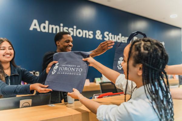 Prospective student getting handed a bag by a staff member in the Admissions & Student Recruitment office
