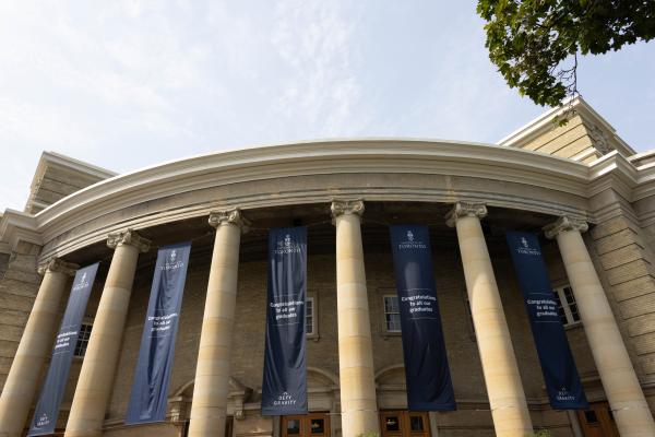 A domed building with tall pillars with blue banners between them that are congratulating new graduates