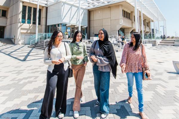 Four students walking and laughing together outside