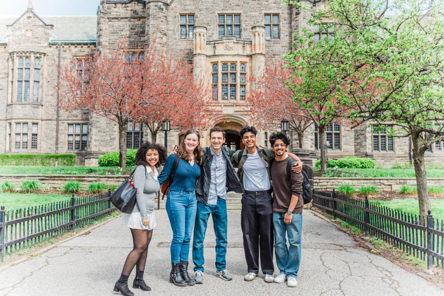 Smiling students standing in front of building.