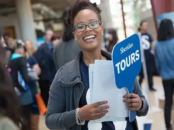 Woman holding a sign that reads "Sheridan Tours".