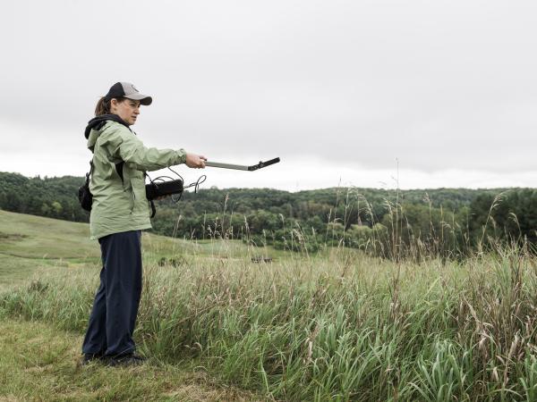 Woman in a field holding an instrument over a field