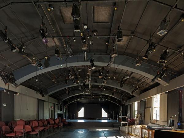 Inside of a dark theatre with a grid of lights on the ceiling