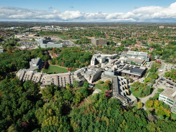 Aerial view of the U of T Scarborough campus surrounded by trees, with a suburban neighborhood in the background