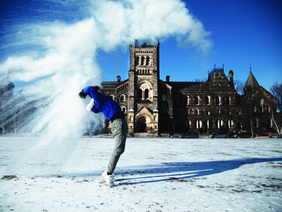 Student standing in snow-covered field throwing snow.