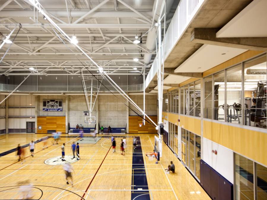 Gymnasium with students running on basketball court.