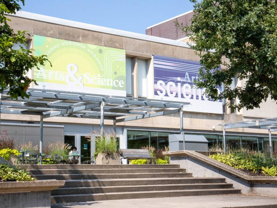 Trees in front of a building with a big sign that says Arts & Science