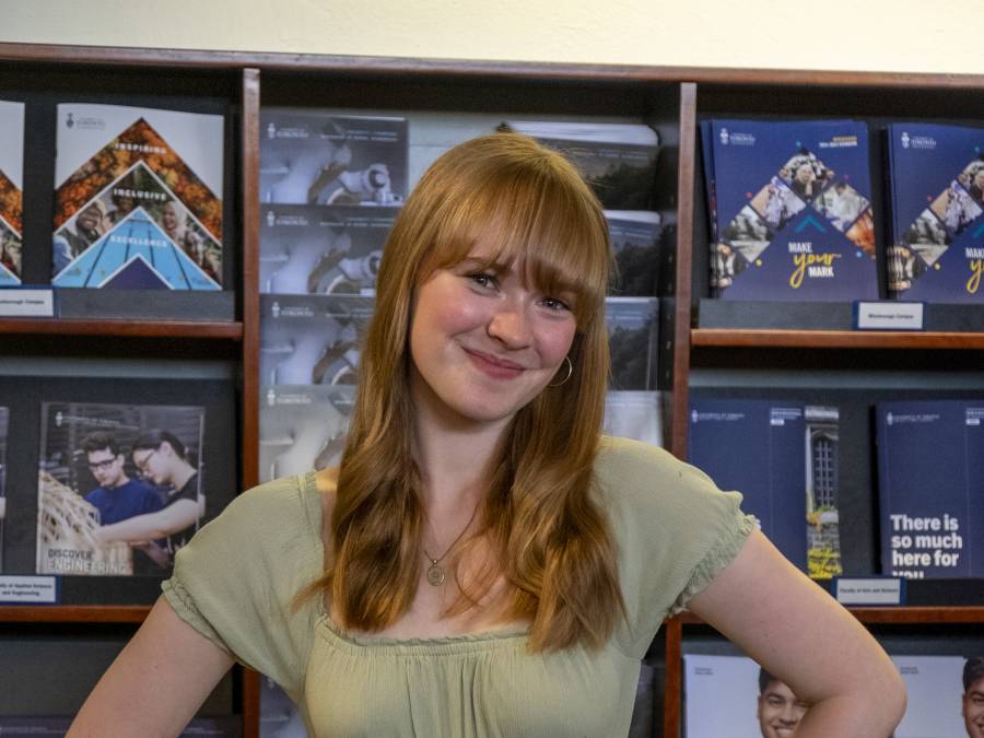 U of T student posing in front of viewbooks