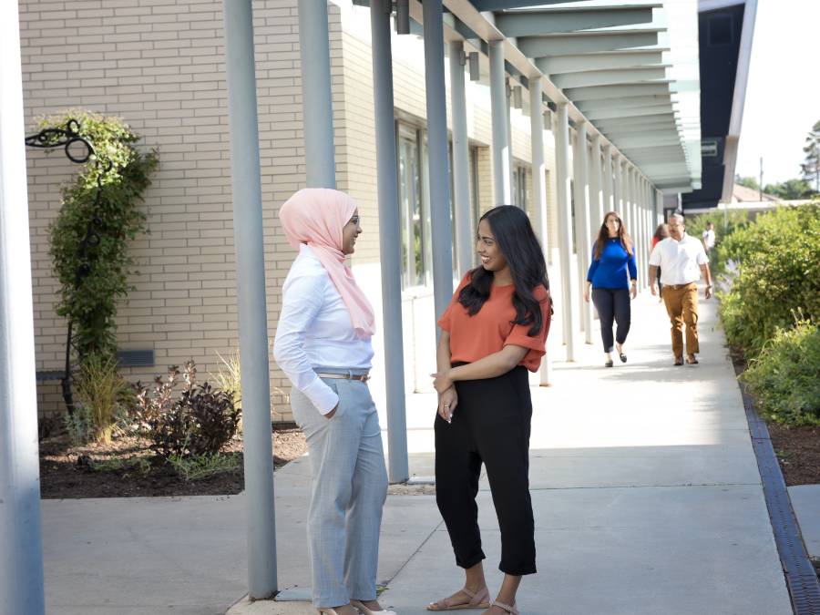 Staff chatting while standing on walkway.