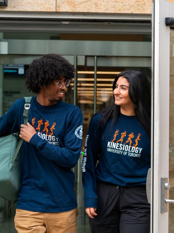 Two Kinesiology students walking out of a building talking to each other