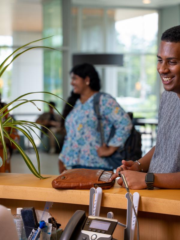 A student asking a question to a staff member at a desk.