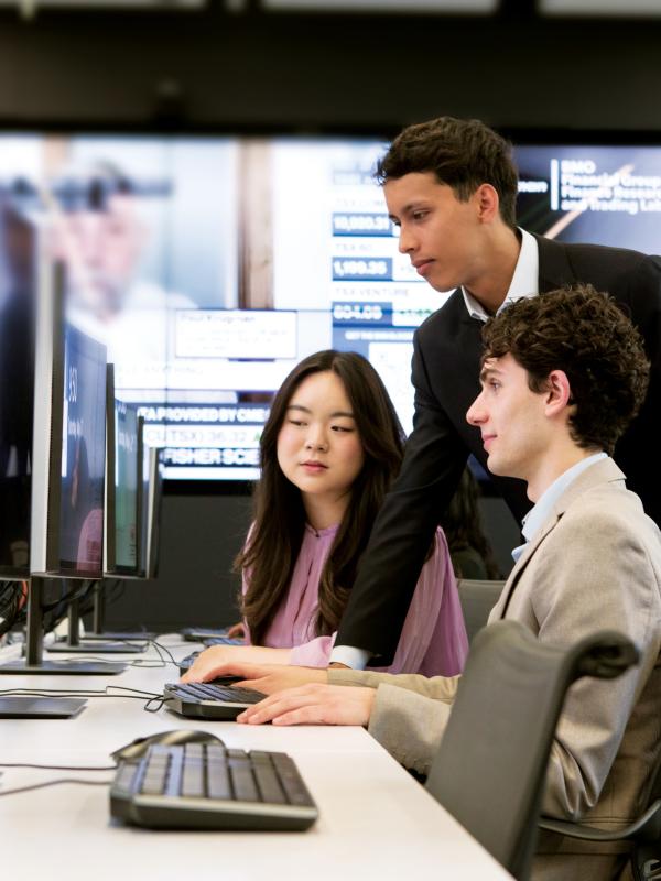 Three students in business clothing sitting at a computer