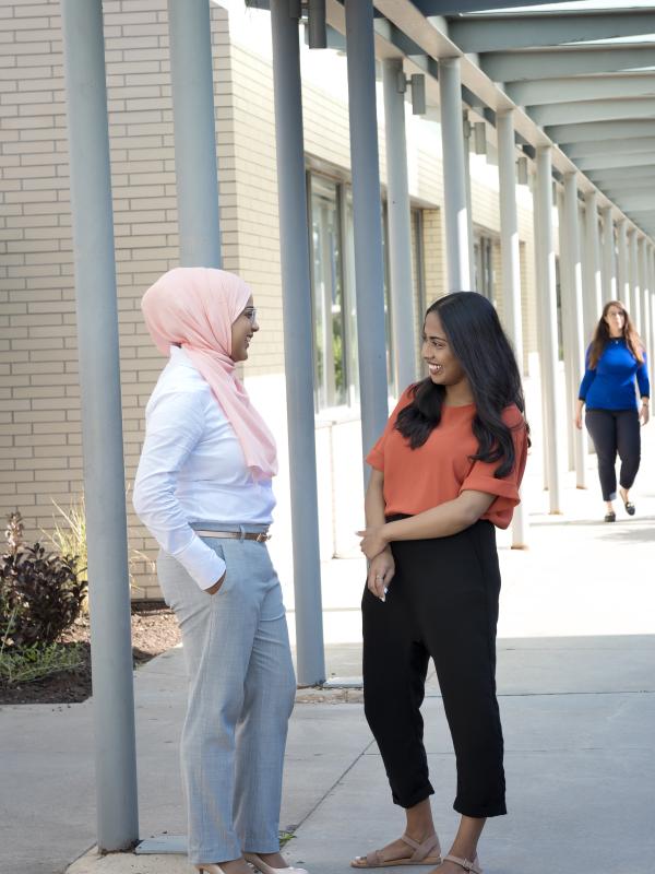 Staff chatting while standing on walkway.