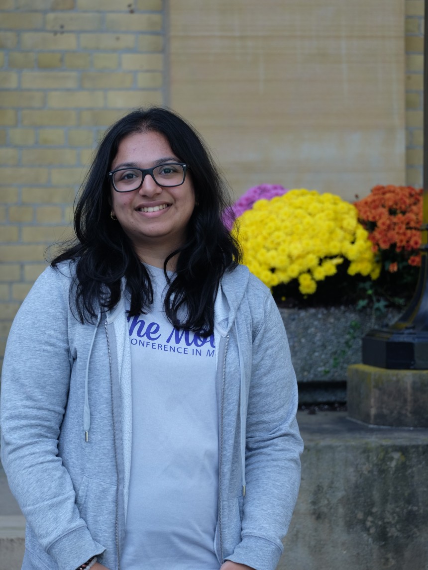 Smiling student standing outside in front of some flowers
