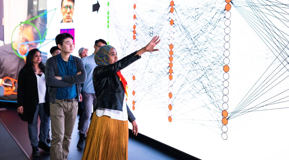 Students standing in front of large touchscreen