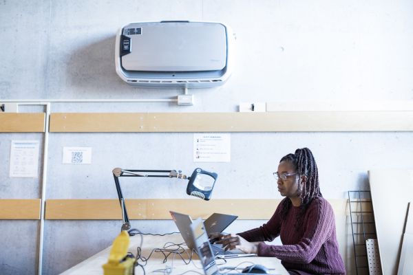 Student sitting using a laptop on a desk with table-mounted magnifying glass/light