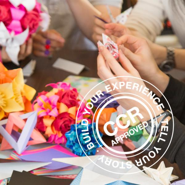 Hands of people making paper crafts with colourful paper and a CCR APPROVED stamp overlaid