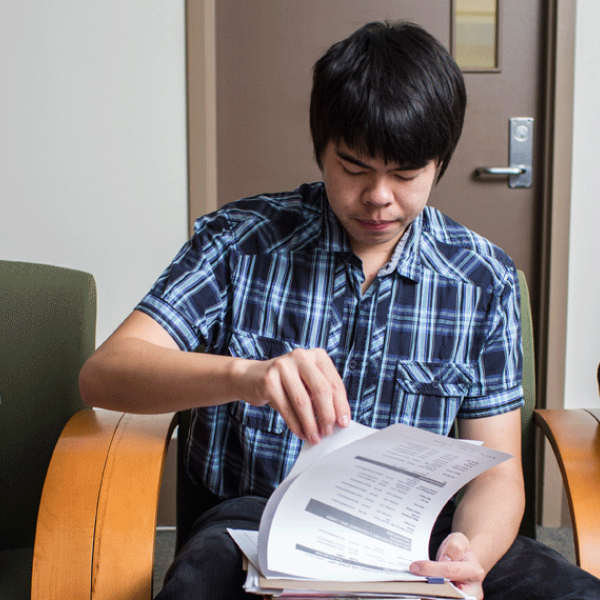 Three students sitting in chairs and reading.