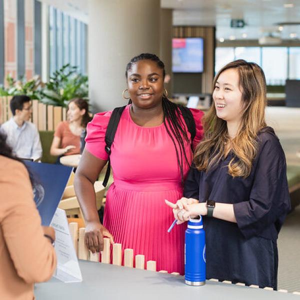 Two students standing at an information desk.
