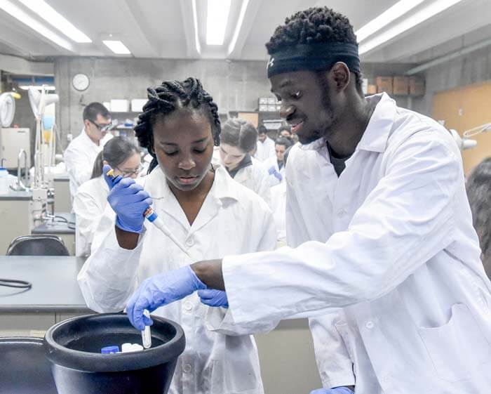 Students in a lab doing lab work wearing lab coats